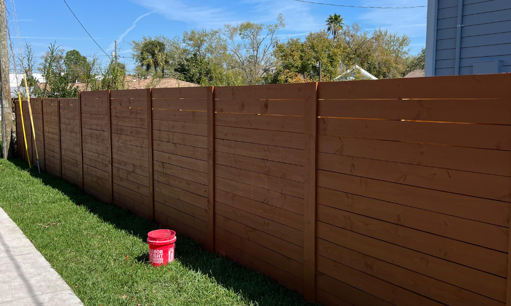 Professional painting of a wooden fence in a residential backyard